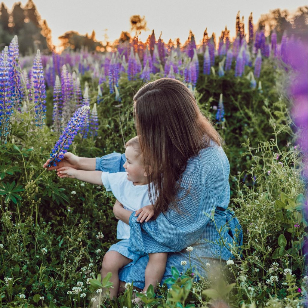 woman sitting with baby on her lap surrounded with purples flower
